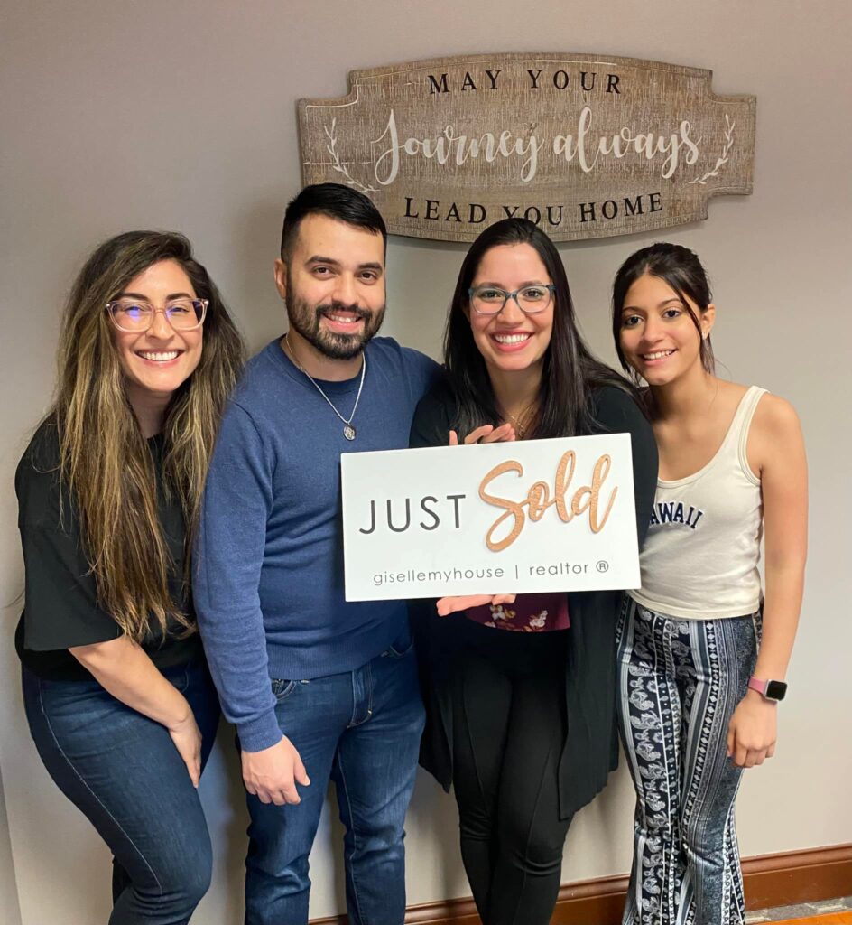 Realtor; Giselle Rodriguez, with family after the closing of their home purchase, holding a Just Sold sign