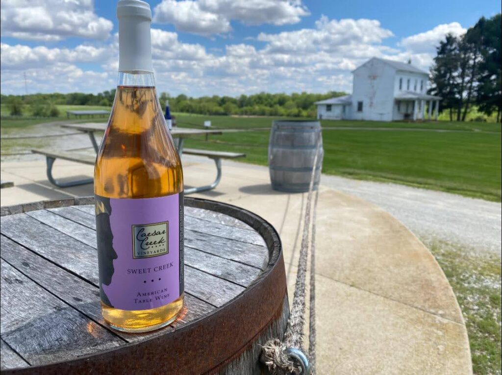 bottle of wine sitting on top of a barrel outside overlooking a gorgeous summer day