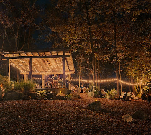 outdoor patio with twinkle lights and pergola nestled between mature trees