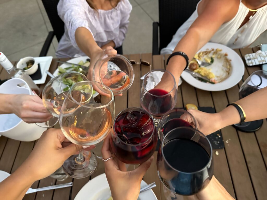 multiple wine glasses with women holding them in a cheers together