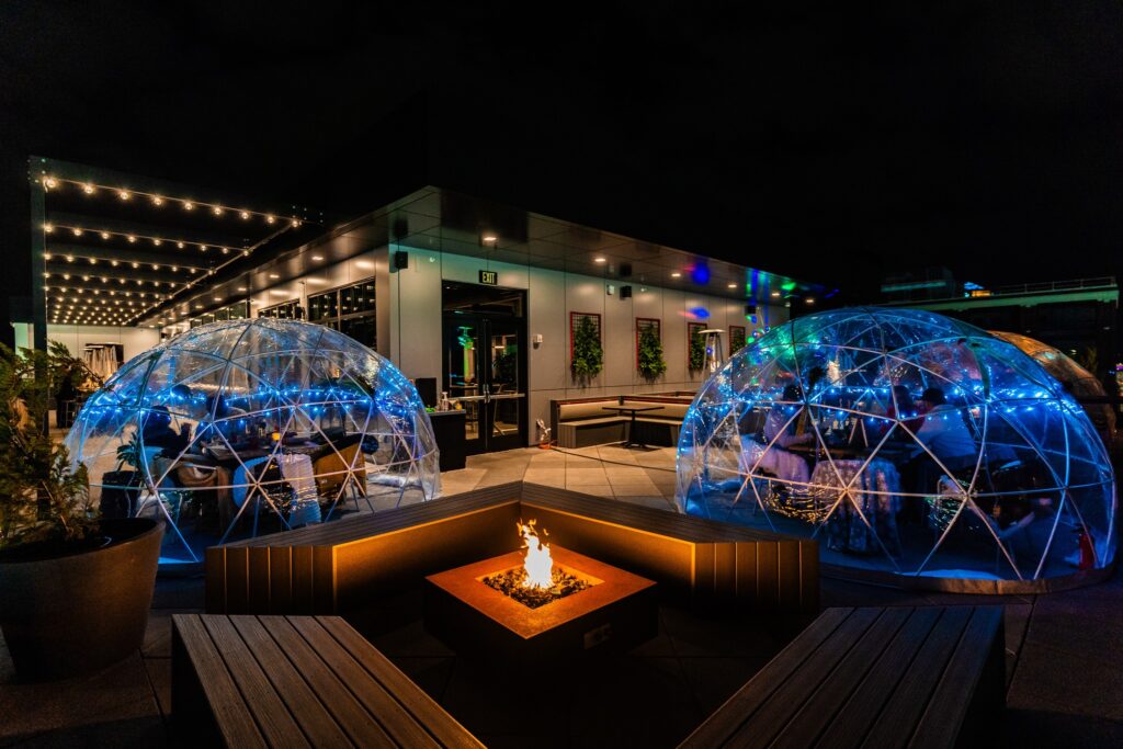 outdoor see through inflatable igloos on a rooftop patio with a fireplace in between