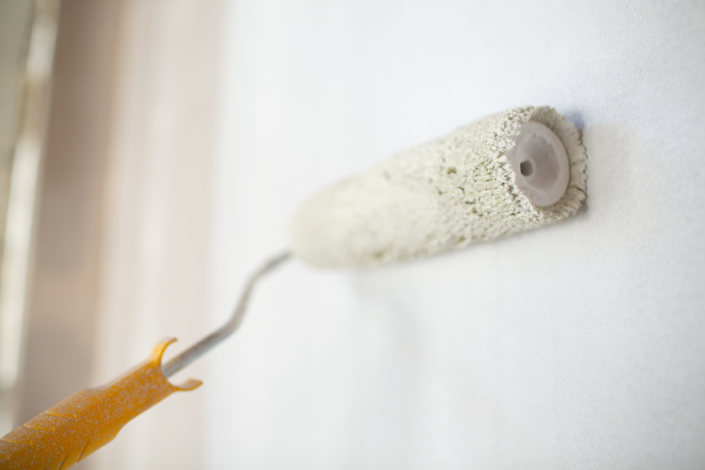 paint roller rolling white paint onto a wall