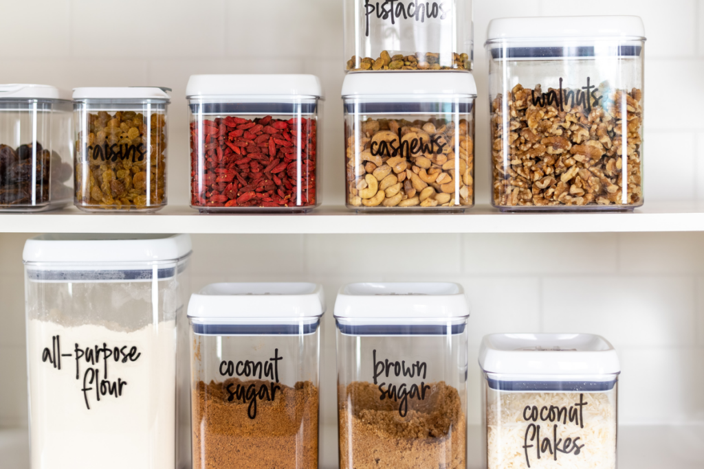 clear bins with food inside each, all with black labels stating what each food is