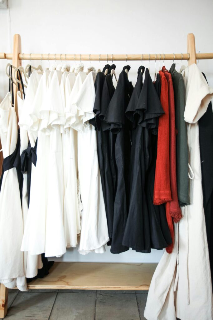 a variety of clothes hanging on a wooden clothes rack