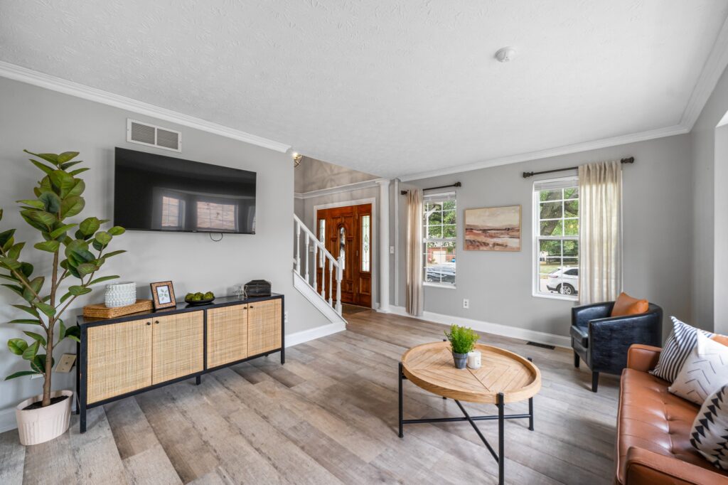 living room with wood floors, a tv, a large indoor plant, and a brown couch